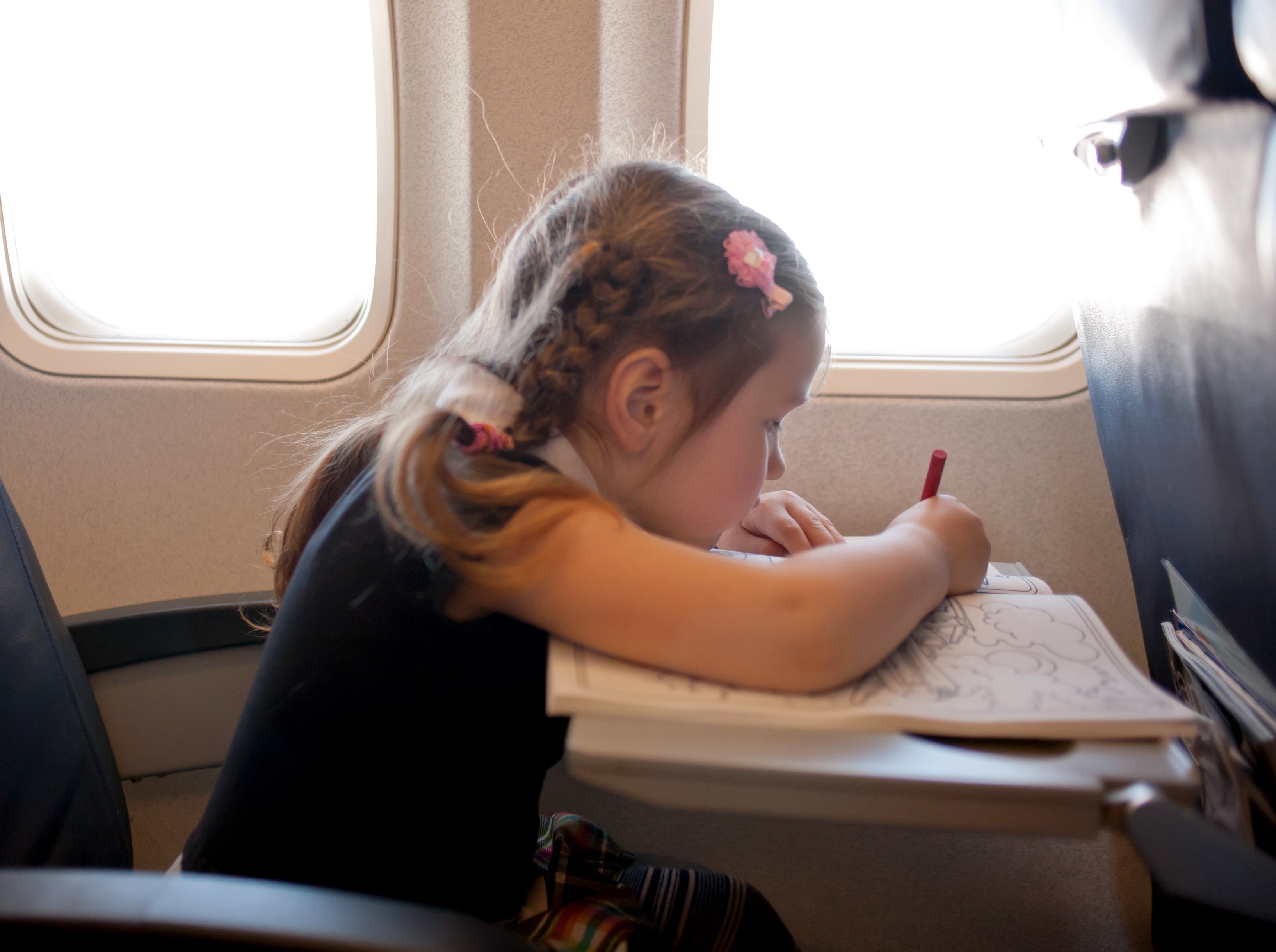 Flugreisen mit Kindern - Fliegen mit Kindern Tipps - Langstreckenflug mit Kindern - Kind malt im Flugzeug