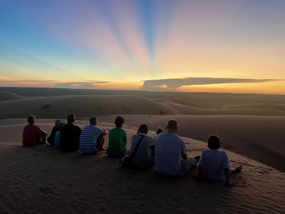 Familienreise Oman - Oman mit Kindern - Gruppe im Oman beobachtet Sonnenuntergang