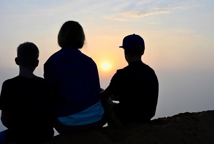 Oman mit Kindern individuell - Oman for family individuell - Familie genießt Sonnenuntergang in der Wüste