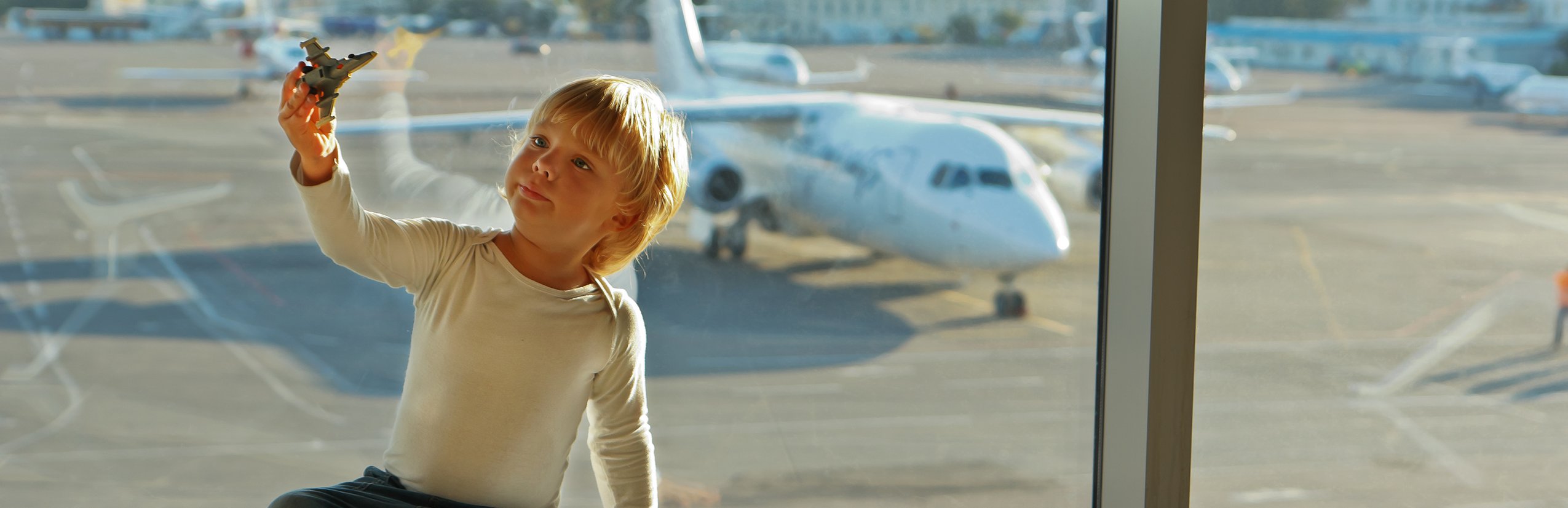 Flugreisen mit Kindern - Fliegen mit Kindern Tipps - Langstreckenflug mit Kindern - Kind spielt mit Flugzeug