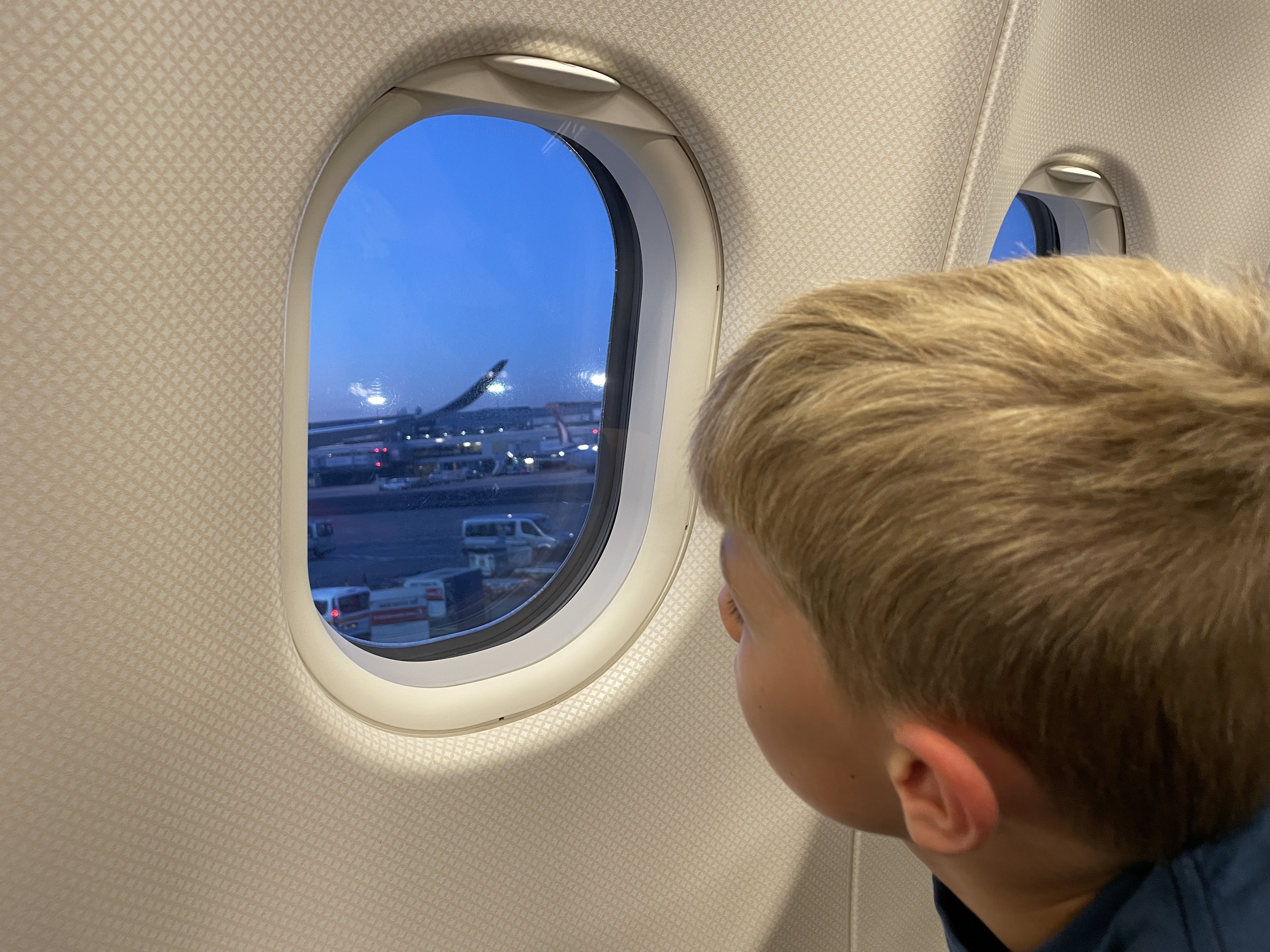 Flugreisen mit Kindern - Fliegen mit Kindern Tipps - Langstreckenflug mit Kindern - Kind schaut aus Fenster